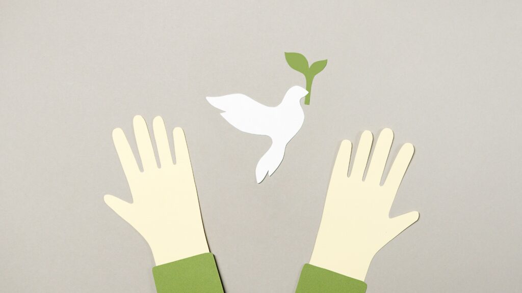 Conceptual image showing cutout hands reaching for a peace dove, symbolizing hope.